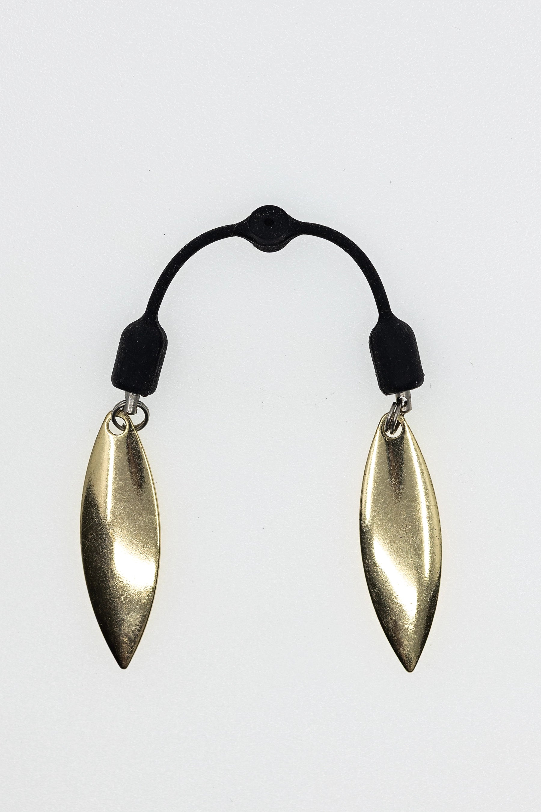 Pair of gold earrings on a black elastic band against a white background